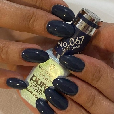 Unhas pintadas de azul escuro segurando dois frascos de verniz