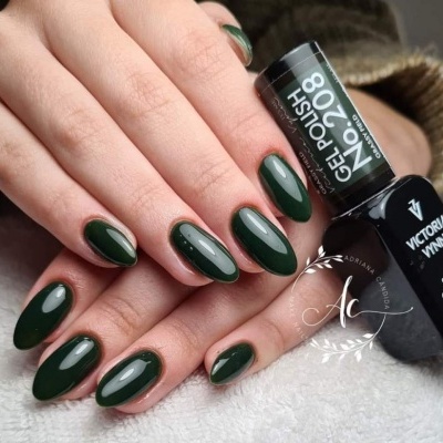 Mãos com unhas postiças verdes brilhantes segurando frasco de verniz gel preto