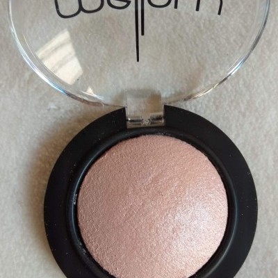 Pó compacto rosa claro em embalagem preta com tampa transparente e texto 'Mefe|om'.