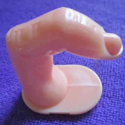 Dedo postiço de plástico cor de pele sobre superfície roxa