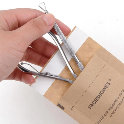 Ferramentas de manicure metálicas numa embalagem de papel castanho com texto FACESHOVES®