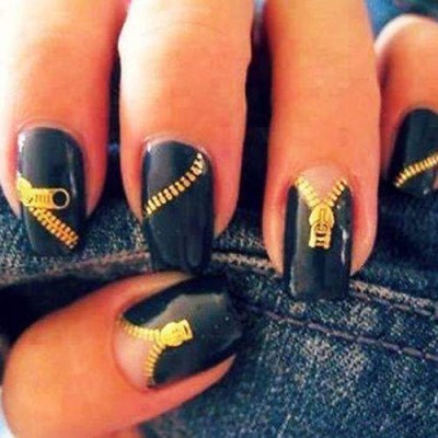 Unhas pretas com desenhos de fechos éclair dourados e fundo de ganga azul
