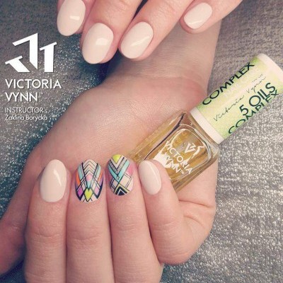 Mãos com unhas nude e decoradas segurando óleo para unhas Victoria Vynn
