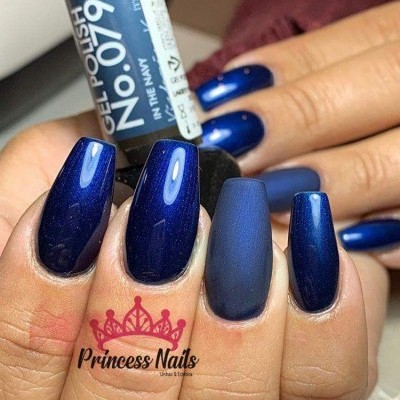 Unhas com verniz gel azul escuro e frasco de verniz 'No 079 IN THE NAVY' nas mãos