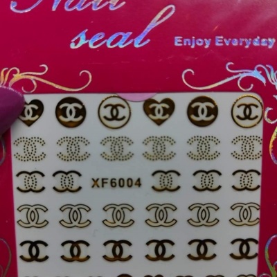 Adesivos para unhas com logotipo 'CC' em dourado e preto na embalagem vermelha