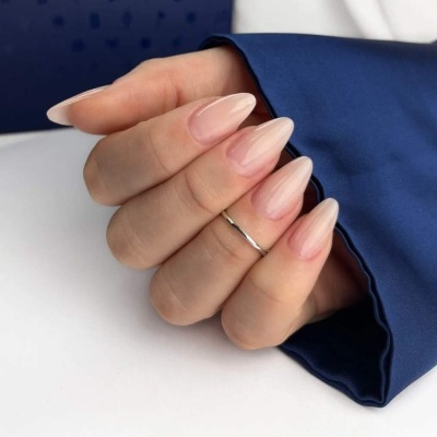 Mão com unhas postiças nude e anel fino prateado 
