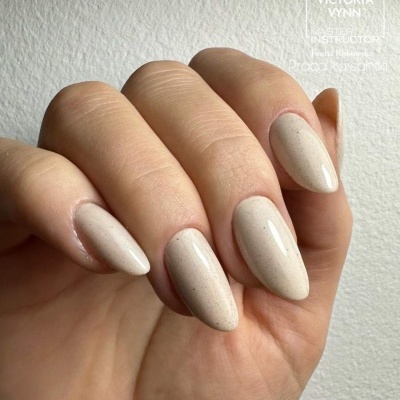 Unhas artificiais bege claro com partículas pretas em fundo branco