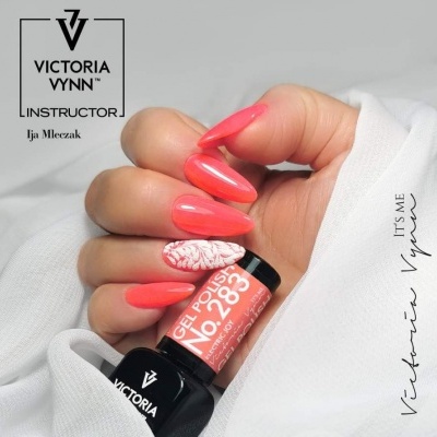 Unhas com verniz gel coral e uma decorada segurando frasco VICTORIA VYNN No. 283