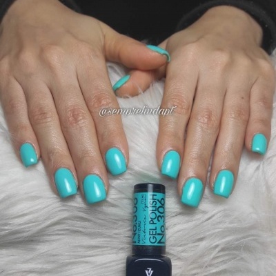 Unhas pintadas de verniz gel azul-turquesa com frasco de verniz Victoria Vynn
