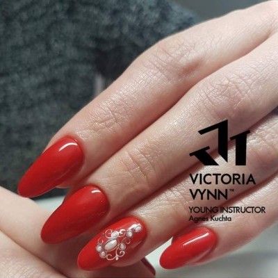 Unhas vermelhas com decoração de pedrinhas brancas e texto VICTORIA VYNN YOUNG INSTRUCTOR Agnes Kuchta