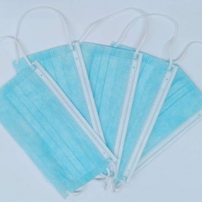 Máscaras descartáveis azuis com elásticos brancos sobre superfície branca