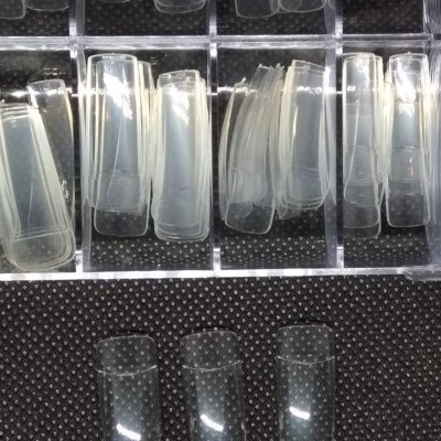 Unhas postiças transparentes organizadas em caixa de plástico com divisórias