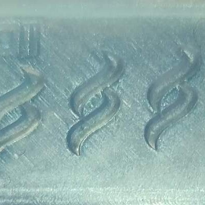 Bloco de cimento cinzento com marcas de fogo em relevo e texto na parte superior