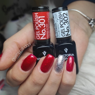 Unhas com verniz gel vermelho e prata segurando frascos de verniz gel Victoria Vynn