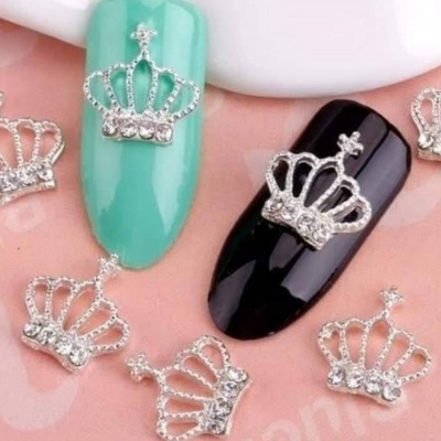 Unhas postiças verde e preta com aplicações de coroas prateadas com pedras brilhantes.