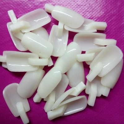 Pontas de unhas artificiais brancas em plástico sobre fundo rosa