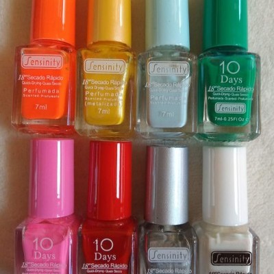 Oito frascos de verniz de unhas Sensinity de várias cores organizados em duas fileiras sobre uma superfície branca.