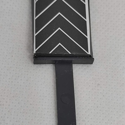 Peça preta com padrão de setas brancas sobre superfície branca