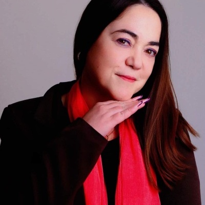 Mulher com lenço vermelho e casaco preto com fundo cinza