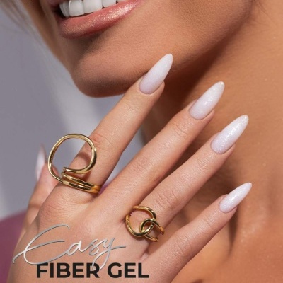 Mão feminina com unhas em gel branco leitoso brilhante e anéis dourados