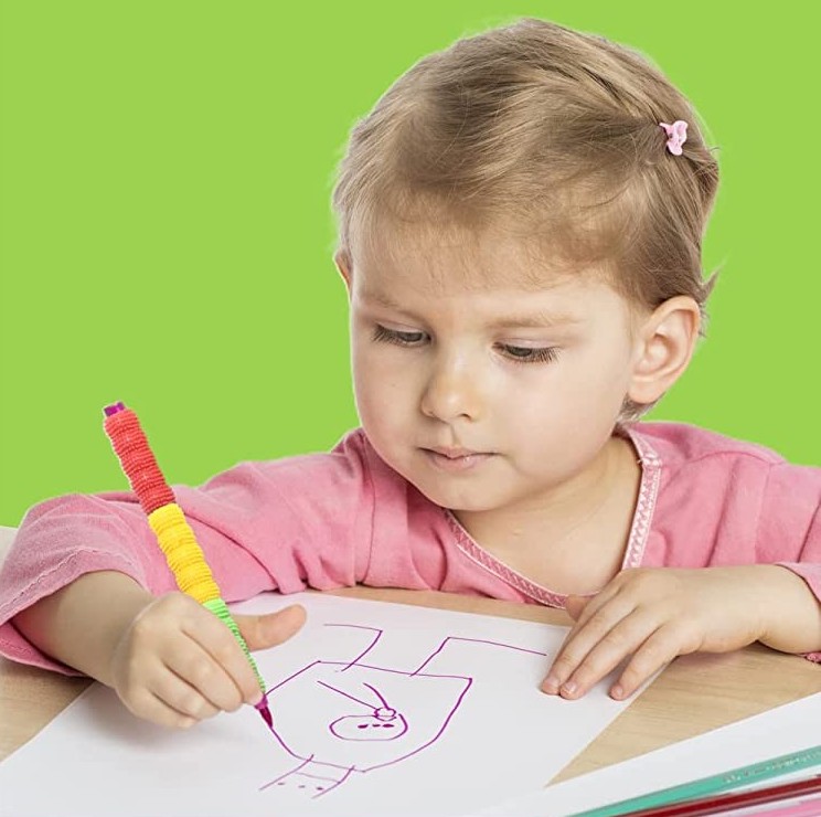 Adaptador para lápis texturizado Criança desenhando com caneta colorida sobre papel numa mesa com fundo verde