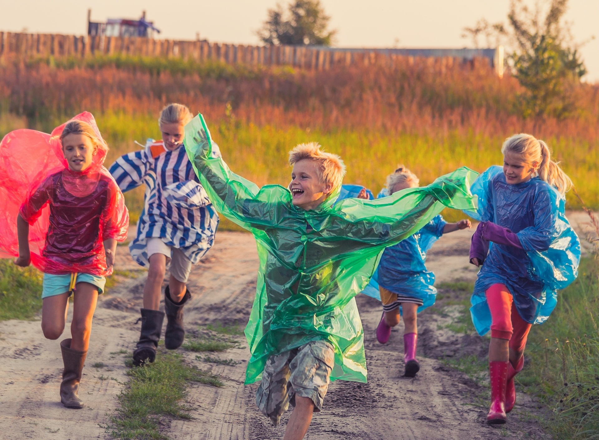 Crianças a correr com capas de chuva coloridas ao ar livre