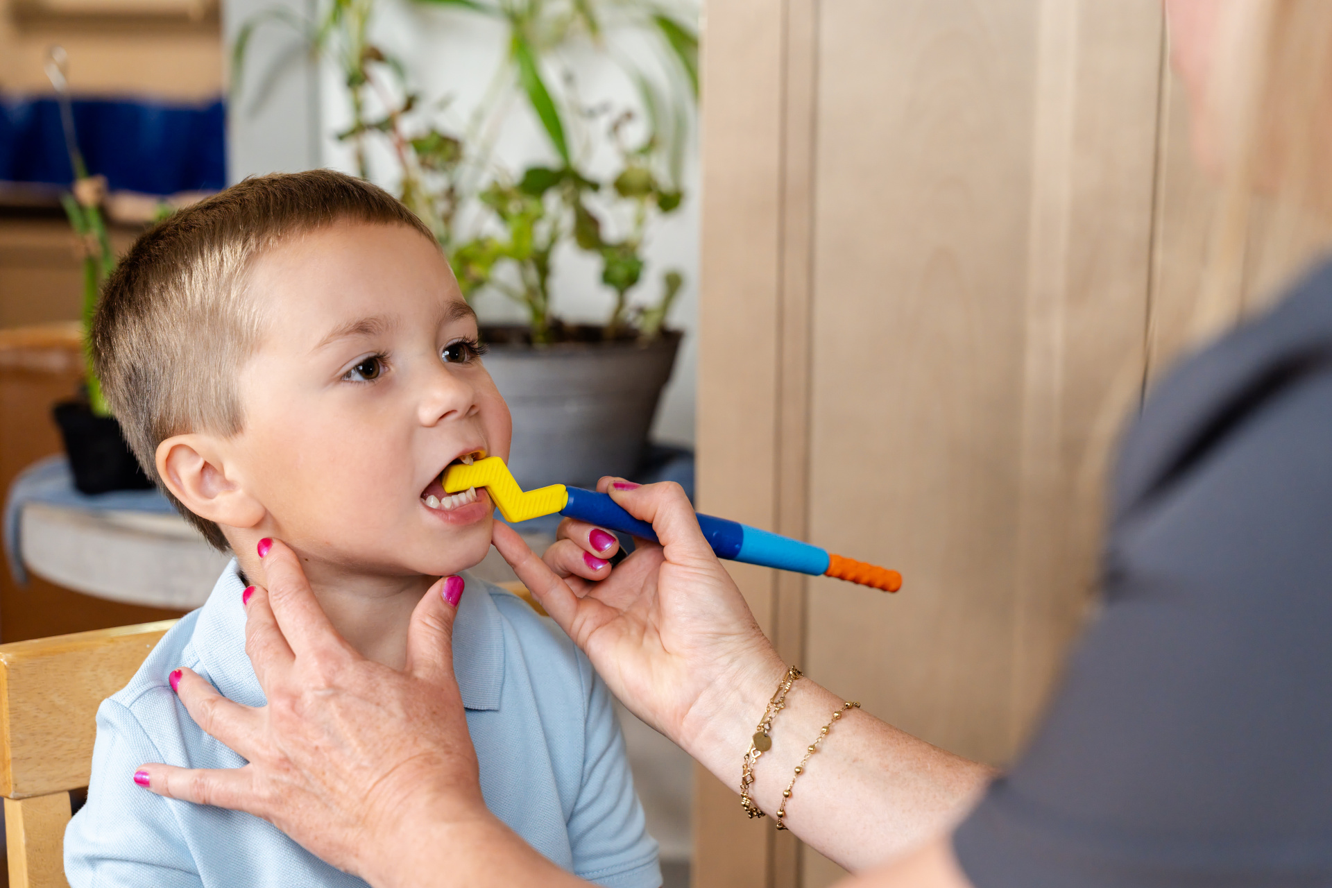 Z-Vibe® Plus da ARK Criança a usar escova dentária infantil azul, laranja e amarela