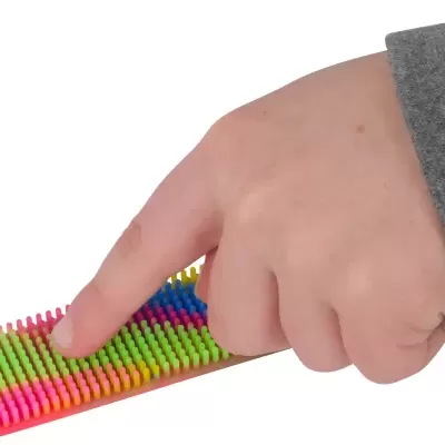 Mão a pressionar brinquedo sensorial com cerdas coloridas