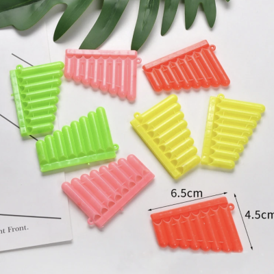 Panflutes coloridos de plástico dispostos sobre uma superfície branca com folhas verdes e papel ao lado