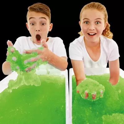 Crianças a brincar com gel verde translúcido em bacias brancas