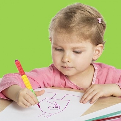 Criança desenhando com caneta colorida sobre papel numa mesa com fundo verde