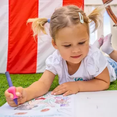 Criança a colorir num livro de atividades no relvado artificial