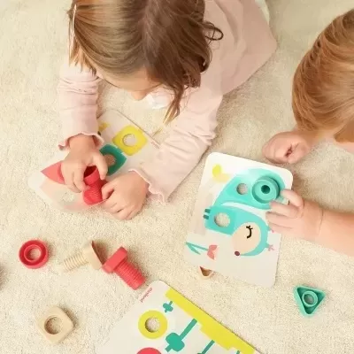 Crianças a brincar com brinquedos de madeira coloridos e cartões em tapete claro