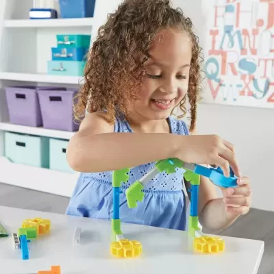 Criança brincando com brinquedo de construção colorido numa mesa branca