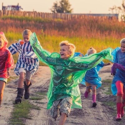Crianças a correr com capas de chuva coloridas ao ar livre