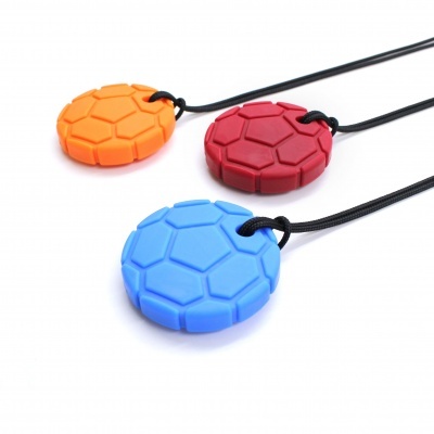 Três pendentes redondos de silicone coloridos com padrão hexagonal suspensos em cordões pretos.