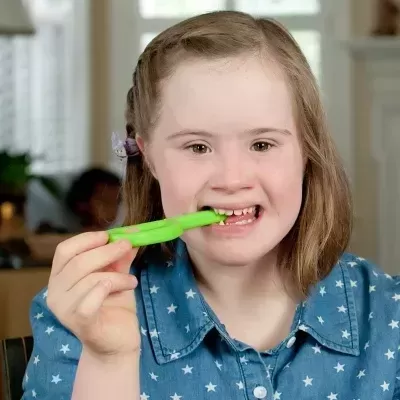 Menina com camisa azul e escova de dentes verde sorrindo