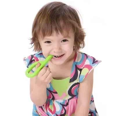 Criança com vestido colorido segurando brinquedo verde em fundo branco
