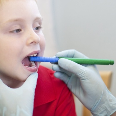 Exame dentário em criança com instrumento azul e verde