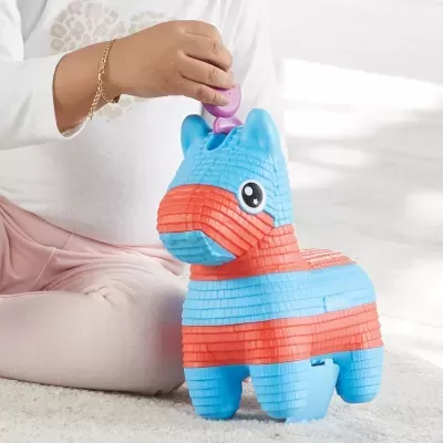 Criança segurando piñata azul e laranja em forma de burro sobre carpete clara