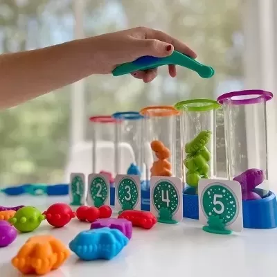 Brinquedo educativo com tubos transparentes, peças coloridas e cartões numerados de 1 a 5