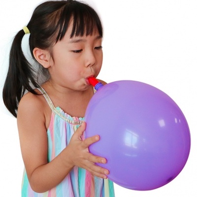 Menina a encher balão roxo com vestido às riscas