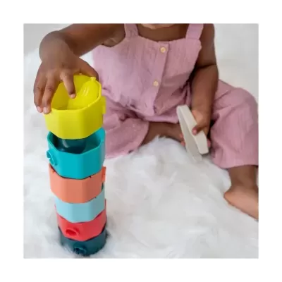 Criança a empilhar blocos coloridos de plástico sentada num tapete branco