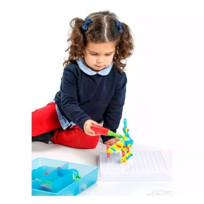 Criança a brincar com jogo de peças coloridas sobre tabuleiro branco