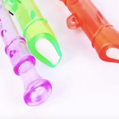 Três apitos de plástico colorido em rosa, verde e vermelho sobre fundo branco.