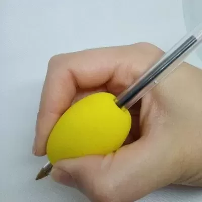 Mão a segurar caneta com pega de espuma amarela em fundo branco