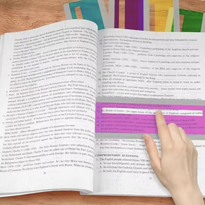 Livro aberto com texto em inglês, destaque rosa e mão apontando.