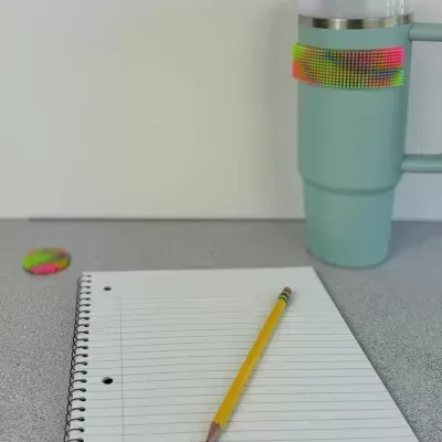 Caderno, lápis e caneca com tira colorida sobre mesa cinza