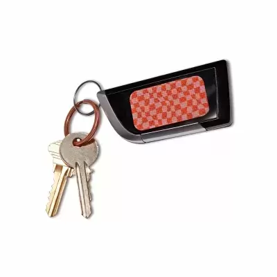 Chaveiro preto com padrão quadriculado vermelho e branco e duas chaves penduradas