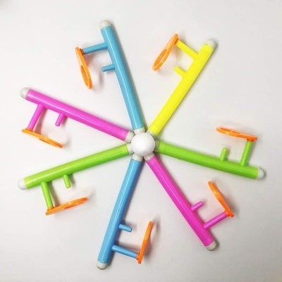 Peças de plástico colorido unidas em roda com suportes laranja sobre fundo branco